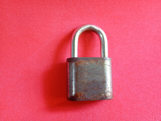 A vintage closed padlock on a red background. Old lock close-up. Confidentiality is secured with a...