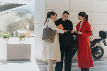 Three professional women in a discussion, showcasing collaboration and teamwork.
