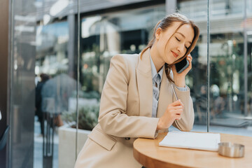 Female professional talking on the phone while making notes, illustrating business productivity in...