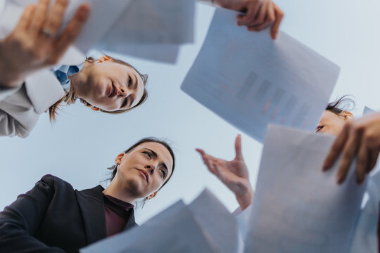 Diverse women collaborate as they review papers under the open sky, symbolizing teamwork and professionalism in a contemporary context.