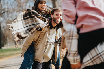 Group of friends enjoying their time outside during a sunny autumn day, spending joyful moments together in a park setting, showcasing friendship, happiness, and seasonal enjoyment.