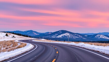 Fototapeta premium an empty road at twilight, with the sky filled with warm hues of pink and purple. the paved highway stretches into the distance, curving around hills under a clear sky