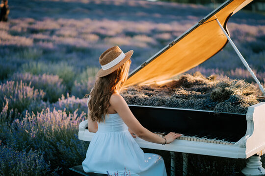 Woman in white dress plays piano in lavender field during sunset with vibrant colors