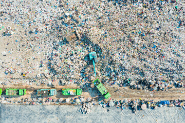 Aerial view of landfill with garbage trucks and excavator managing waste, illustrating...