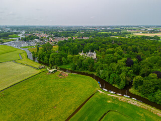 An aerial view of a peaceful countryside with dense forest, a large brick house, and a nearby...