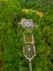 An aerial view of a historic mansion surrounded by lush green trees and a beautifully landscaped...