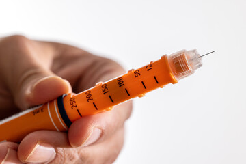 Drop of Orange Insulin Needle in Male Hand on White Background
