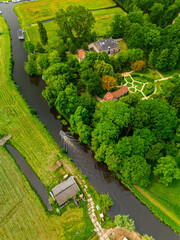 An aerial view of a peaceful countryside with dense forest, a large brick house, and a nearby...