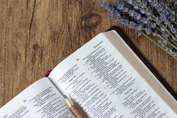 Open holy bible book with lavender flowers on wooden background. Top view. Copy space. Scripture...