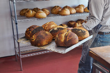 Close Up Of Male Baker Taking Sourdough Loaves Out Of Oven With Paddle In Bakery