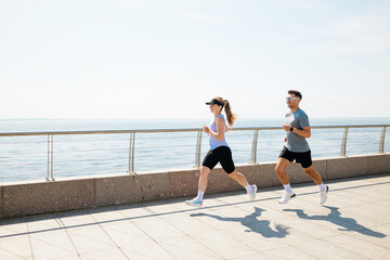 Couple runs along the waterfront on a sunny morning, embracing fitness and nature