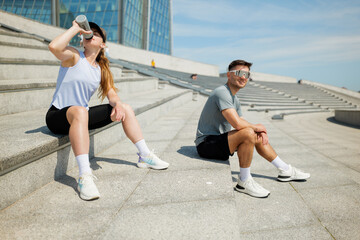 Couple enjoying a sunny workout break at an urban outdoor fitness area