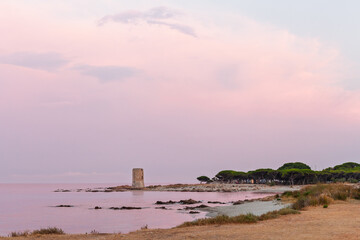 Coastal watchtower by calm sea under soft pastel sky during twilight at Mediterranean beach
