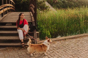 Close-up of a woman with Welsh Corgi in a park on a hot sunny day. Concept of pet care and...