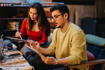 Candid image of two young individuals engaged in painting during an art session, showcasing creativity, focus, and collaboration in a cozy and artistic environment.