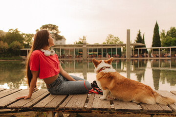 Close-up of a woman with Welsh Corgi in a park on a hot sunny day. The dog looks tired from the...