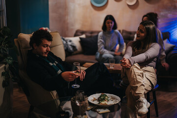 Friends gathered at a cozy living room setting, enjoying drinks and conversation. The atmosphere is relaxed and inviting, fostering a sense of togetherness and comfort.