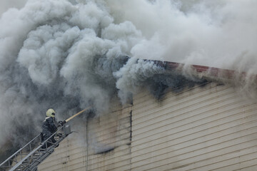 Firefighter Extinguishing Burning Building with Heavy Smoke During Emergency Rescue Operation