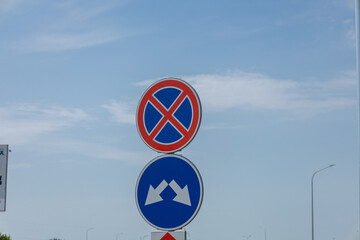A no parking sign and a directional arrow are positioned along a road under a clear blue sky with...