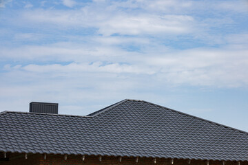 Metallic roofing features a sleek tiled design, reflecting sunlight under a clear blue sky at a...