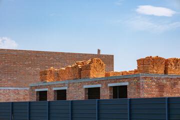 Workers are preparing a building structure with numerous bricks neatly piled on top of a partially...