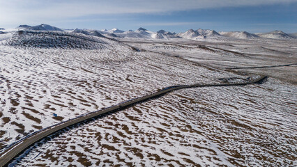aerial A snow-covered road vanishes into a white, silent landscape symbolizing isolation, purity,...
