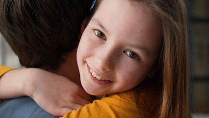 Positive Caucasian family little girl embracing dad male father parent cuddling hug at home happy...