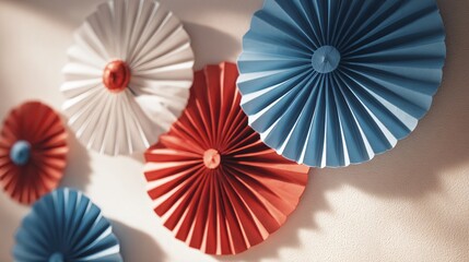 Obraz premium Paper fan decorations in red, white, blue on pale wall, space between