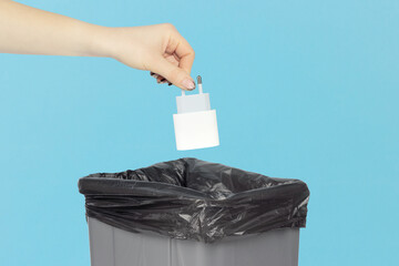 Throw network charger for phone in trash, outstretched hand with network charger for phone in front of trash can. Concept of using original devices