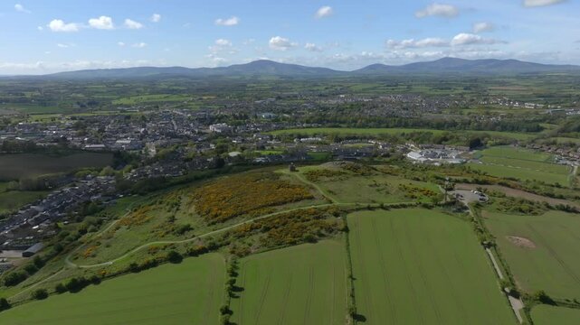 Vinegar Hill, Enniscorthy, County Wexford, Ireland, April 2025. Drone high angl panoramic overview of parking lot leading to stone tower monument with nearby town buildings sprawling across fields.
