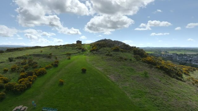 Vinegar Hill, Enniscorthy, County Wexford, Ireland, April 2025. Drone ascends to establish historic battle grounds with neatly mowed lawn as sun breaks between clouds illuminating the grass.