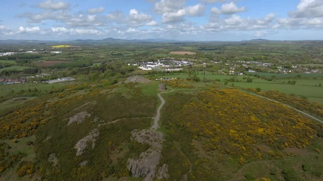 Vinegar Hill, Enniscorthy, County Wexford, Ireland, April 2025. Drone slow approach to stone tower monument with gentle clockwise orbit as cloud shadow passes and sunlight illuminates the greenery.