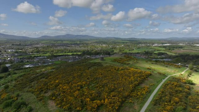Vinegar Hill, Enniscorthy, County Wexford, Ireland, April 2025. Drone establishing orbit counterclockwise slowly pulls away with cloud shadow darkening the lush green landscape.