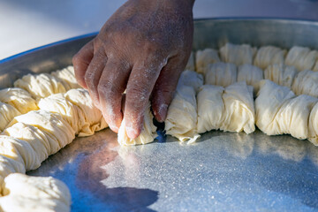 Close-Up of a Woman's Hand Shaping the Dough She Rolled and Arranging It on a Tray to Make a Dessert
