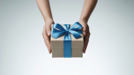 Hands holding a simple kraft paper gift box tied with a luxurious blue satin ribbon
