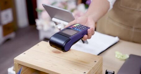Credit card being inserted into POS terminal during cashless transaction in flower shop operated by Asian elderly florist running successful small business after retirement - Powered by Adobe
