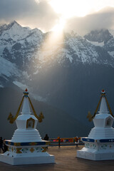  golden Tibetan stupa illuminated by ethereal light, standing against a majestic mountain backdrop....