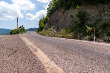 Winding road in the countryside in the mountains with blue sky and clouds.