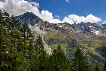 Scenic view of rugged alpine mountains in Switzerland with rocky peaks, green slopes, and scattered...