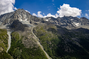 Scenic view of rugged alpine mountains in Switzerland with rocky peaks, green slopes, and scattered...