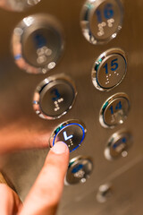 An unrecognizable person selecting the L or Lobby floor by pressing one of the elevator buttons with his or her finger
