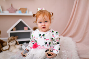 Little beautiful girl with red hair in bright decor in photo studio. baby