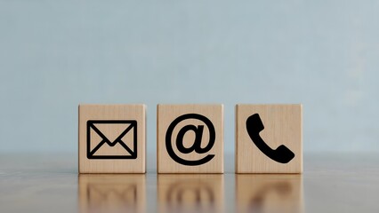 Contact us concept displaying email, at sign, and phone icons on wooden cubes against a neutral background, presenting modern communication options for information or support.