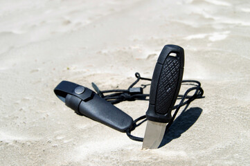 Hunting knife with a short blade lies on sand