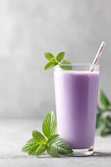 Refreshing purple mint smoothie served in a clear glass with mint leaves on a gray background