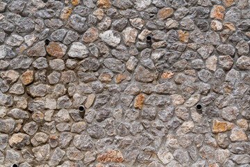 View of the stone wall with water drainage pipes.