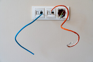 Installation of new network, cable tv, and electric outlets on a white wall.