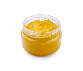 Yellow condiment or mustard in a glass jar on a white background for culinary use