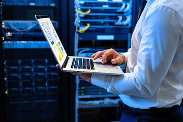 Technician working with laptop in server room technology data center