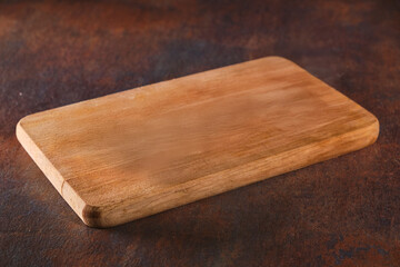 Empty wood cutting board on dark background. Empty wooden cutting board on a brown texture...